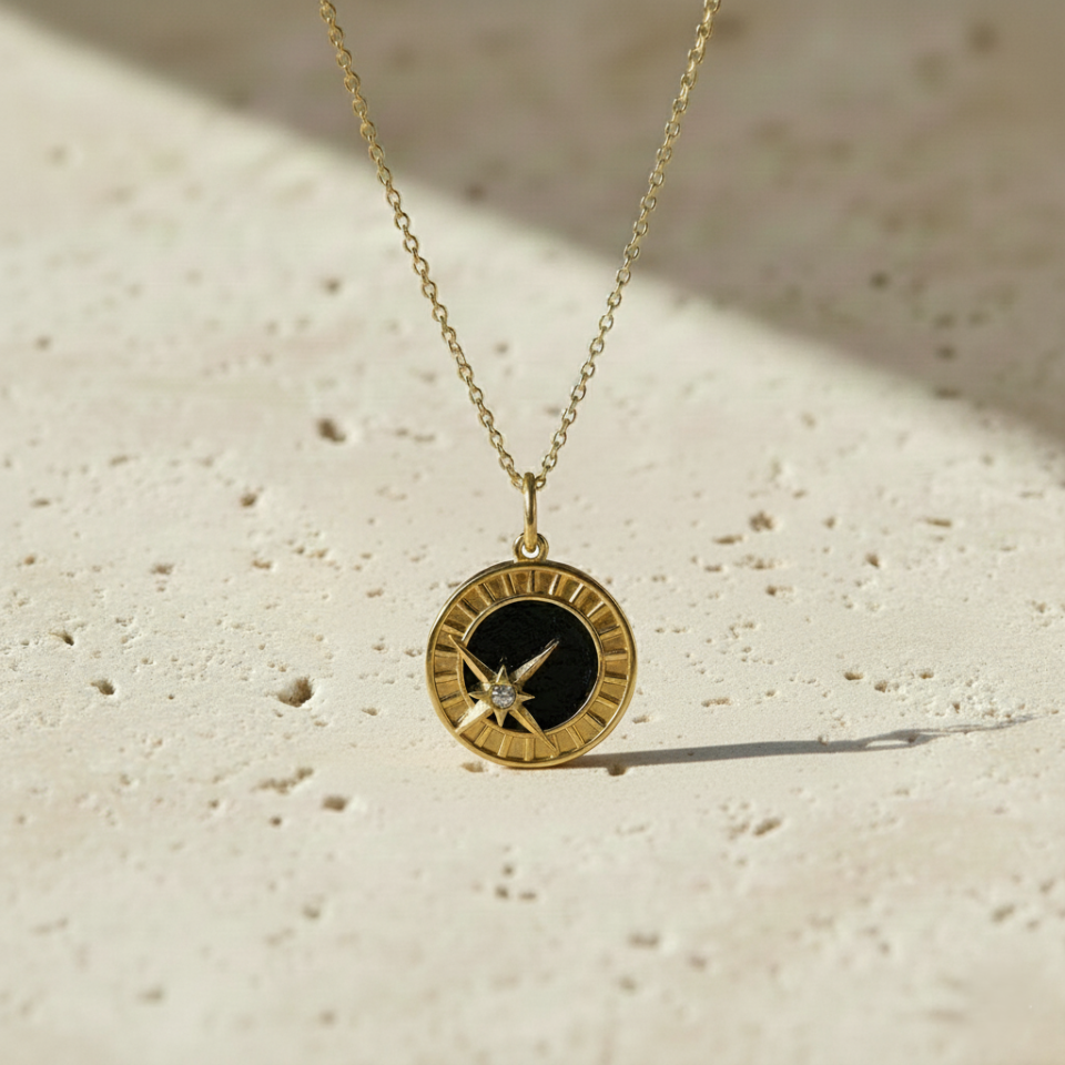 Gold starburst pendant with black enamel center on chain