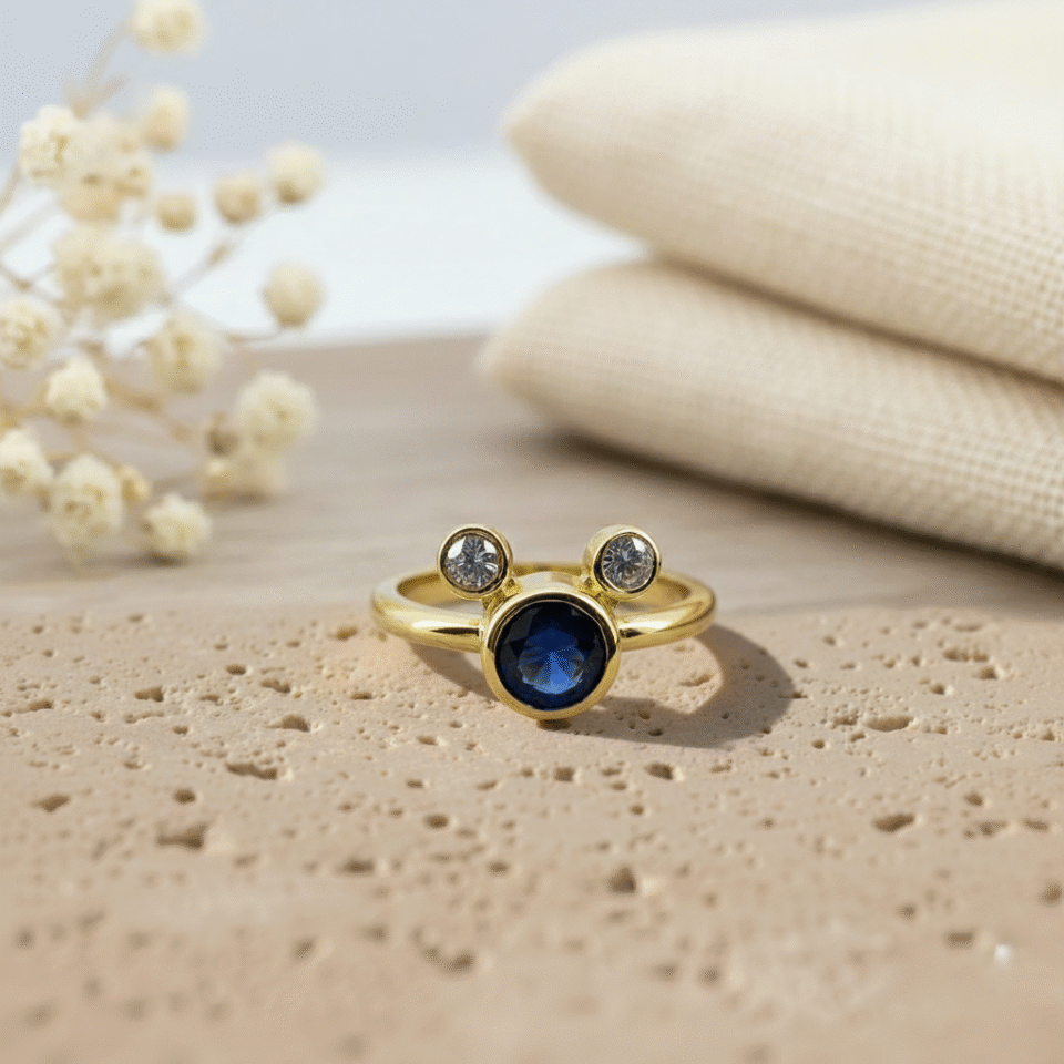 Gold-plated Mickey Mouse–inspired ring with a deep blue center stone and CZ sparkle, crafted with premium detailing by a leading jewelry manufacturer in Jaipur.